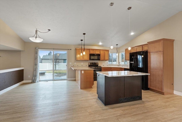 kitchen featuring a center island, hanging light fixtures, light countertops, light wood-type flooring, and black appliances