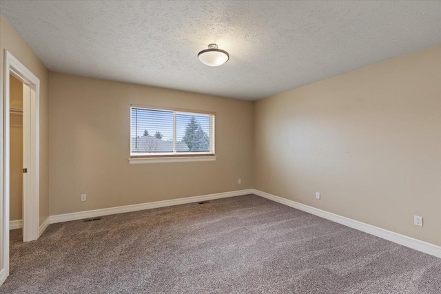 carpeted empty room with a textured ceiling and baseboards