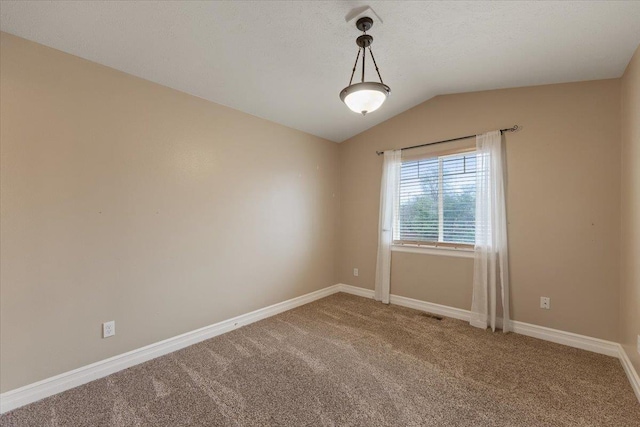 carpeted spare room featuring vaulted ceiling, visible vents, and baseboards