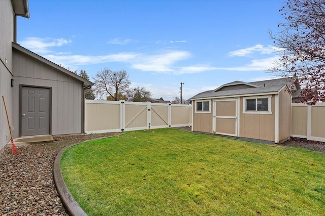 view of yard featuring a storage shed, a fenced backyard, a gate, and an outdoor structure