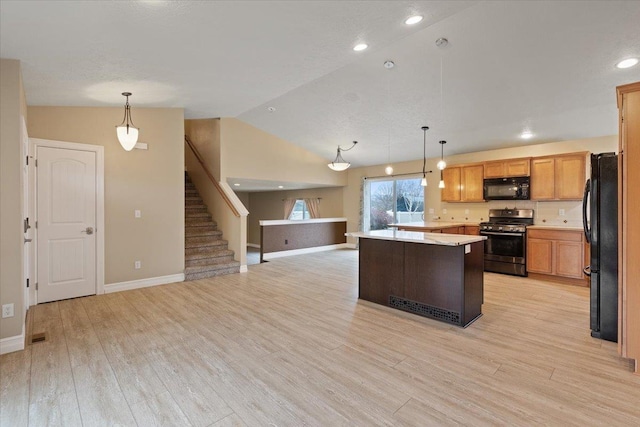 kitchen with pendant lighting, light countertops, open floor plan, a kitchen island, and black appliances