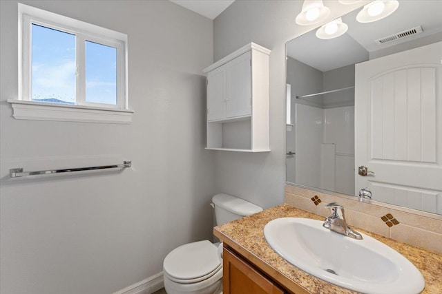 bathroom featuring toilet, vanity, visible vents, baseboards, and walk in shower