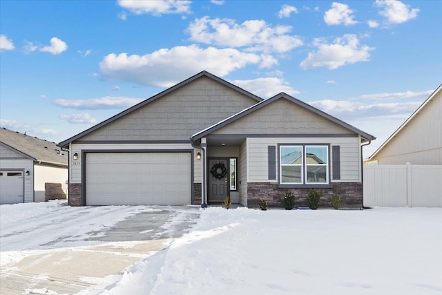 view of front of property featuring stone siding, an attached garage, and fence