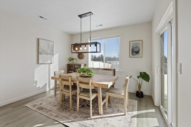 dining area featuring visible vents, a textured ceiling, and wood finished floors