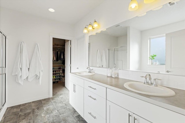 bathroom featuring a spacious closet, a sink, visible vents, and a shower stall