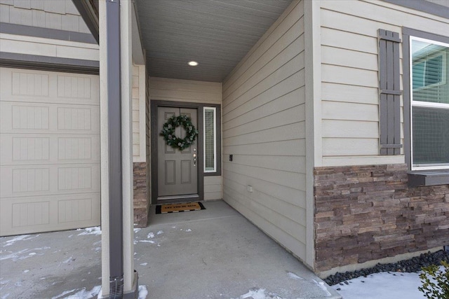 snow covered property entrance with stone siding