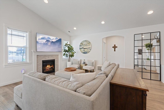 living room with lofted ceiling, recessed lighting, baseboards, a brick fireplace, and light wood-type flooring