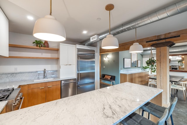 kitchen with white cabinetry, a sink, hanging light fixtures, and high quality appliances