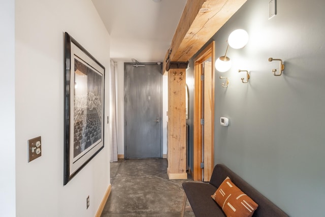 hall featuring baseboards and concrete flooring