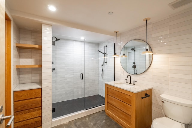 full bath featuring toilet, vanity, visible vents, tile walls, and a stall shower