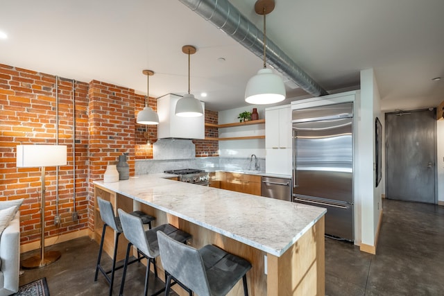 kitchen featuring a peninsula, light stone countertops, open shelves, high end appliances, and pendant lighting