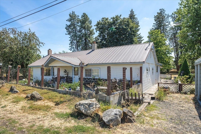 view of front of property with a chimney, fence, and metal roof