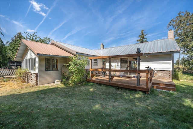 back of property with metal roof, a lawn, a chimney, and a wooden deck