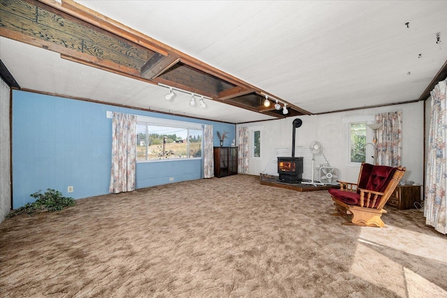 unfurnished living room with carpet, a wood stove, rail lighting, and crown molding