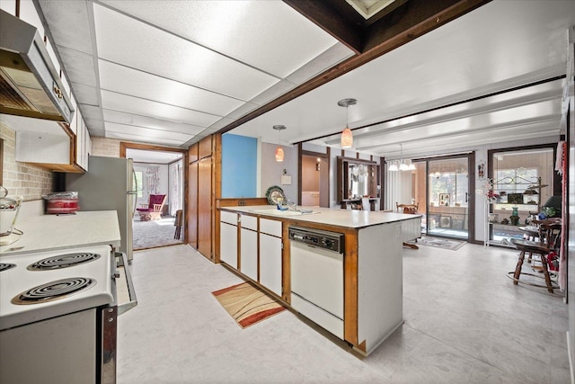 kitchen featuring a paneled ceiling, white appliances, light countertops, range hood, and decorative light fixtures