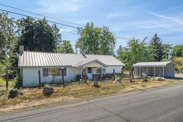 ranch-style house with metal roof, a chimney, fence, and a detached carport