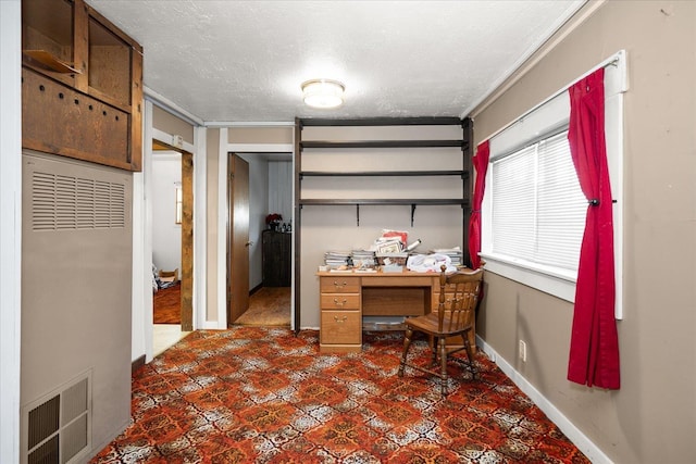 office space featuring baseboards, visible vents, a heating unit, and a textured ceiling