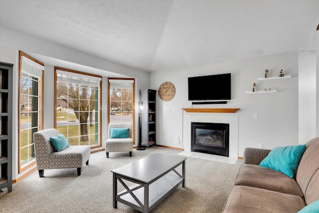 living room featuring baseboards, light colored carpet, a textured ceiling, and a tiled fireplace