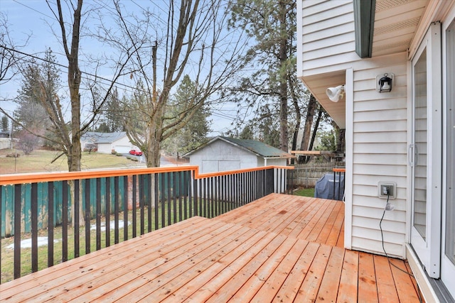 wooden deck featuring fence, a storage unit, a lawn, and an outdoor structure