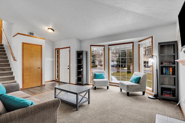 living room featuring visible vents, lofted ceiling, stairway, a textured ceiling, and carpet flooring