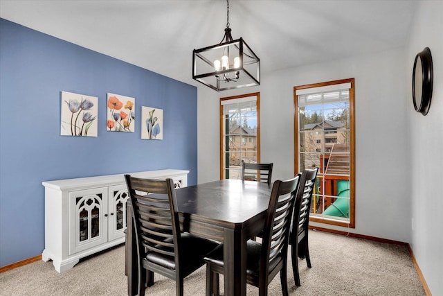 dining area with light colored carpet, a notable chandelier, and baseboards