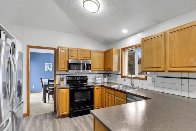 kitchen featuring dark countertops, stainless steel appliances, a sink, and lofted ceiling