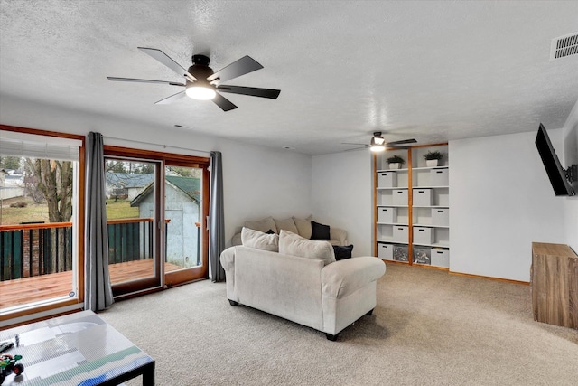 living room featuring light carpet, a ceiling fan, visible vents, and a textured ceiling