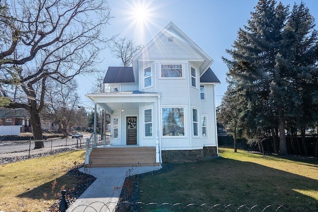 victorian house featuring a porch, fence, and a front lawn