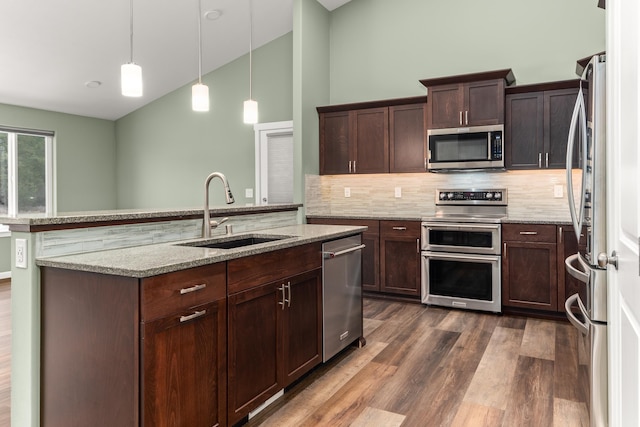 kitchen featuring dark brown cabinetry, stainless steel appliances, dark wood-style flooring, a sink, and hanging light fixtures