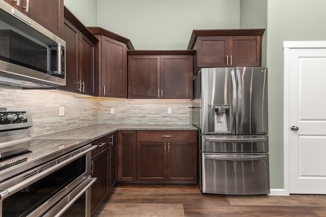 kitchen featuring dark wood-style floors, appliances with stainless steel finishes, backsplash, and light stone counters