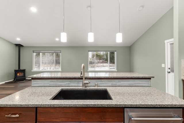 kitchen featuring light stone counters, a sink, open floor plan, hanging light fixtures, and dishwasher