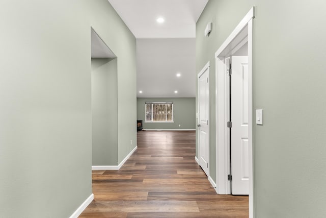 hallway featuring baseboards, wood finished floors, and recessed lighting