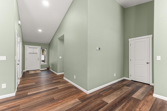 entryway with dark wood-style floors, a high ceiling, and baseboards