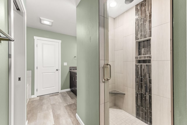 bathroom featuring a stall shower, baseboards, wood finished floors, and vanity