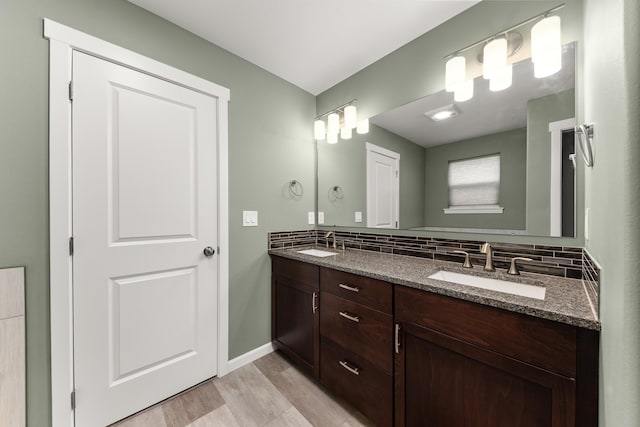 full bath with double vanity, baseboards, backsplash, and a sink