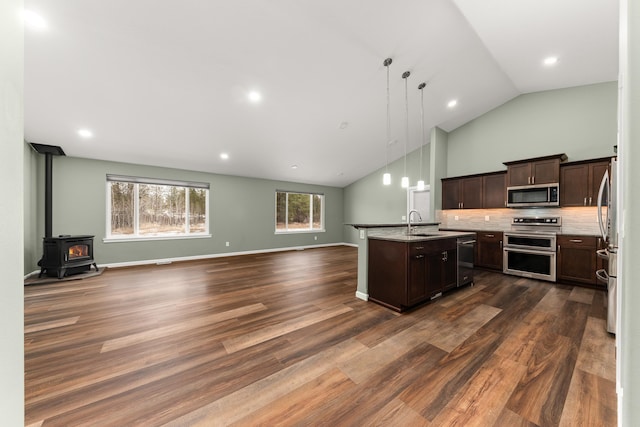 kitchen with dark wood finished floors, open floor plan, a kitchen island with sink, stainless steel appliances, and dark brown cabinets