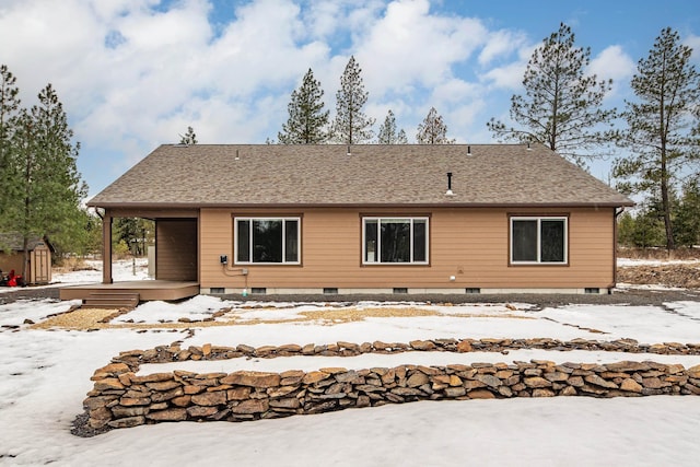 rear view of house featuring a shingled roof and an outbuilding