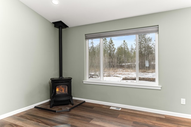 room details featuring wood finished floors, a wood stove, and baseboards