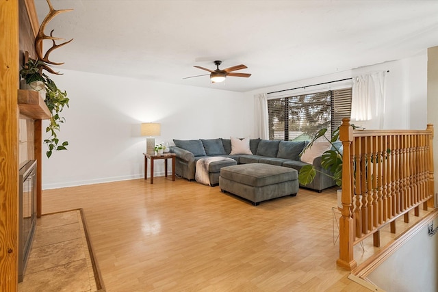 living room with baseboards, ceiling fan, and light wood finished floors