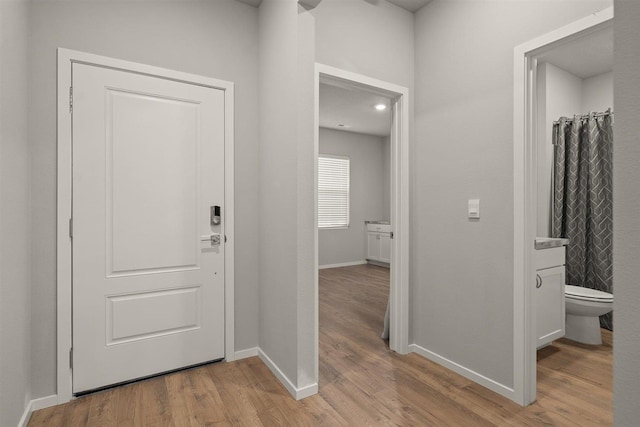 corridor with light wood finished floors and baseboards