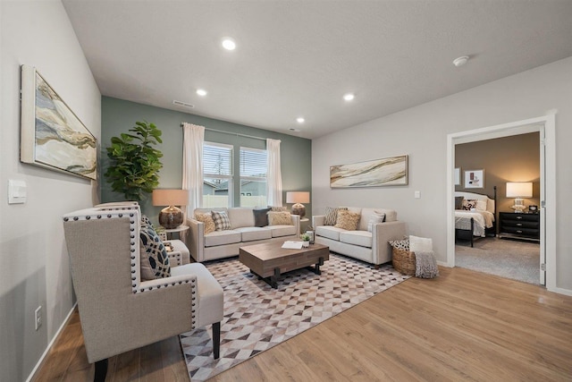 living area featuring baseboards, visible vents, wood finished floors, a textured ceiling, and recessed lighting