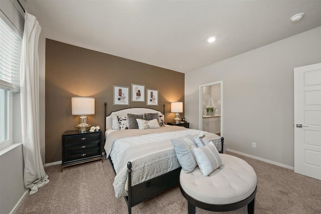 carpeted bedroom featuring baseboards and connected bathroom