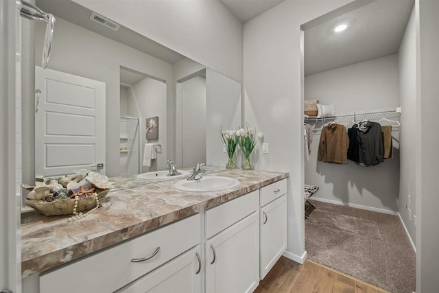 full bathroom with wood finished floors, vanity, visible vents, baseboards, and a spacious closet