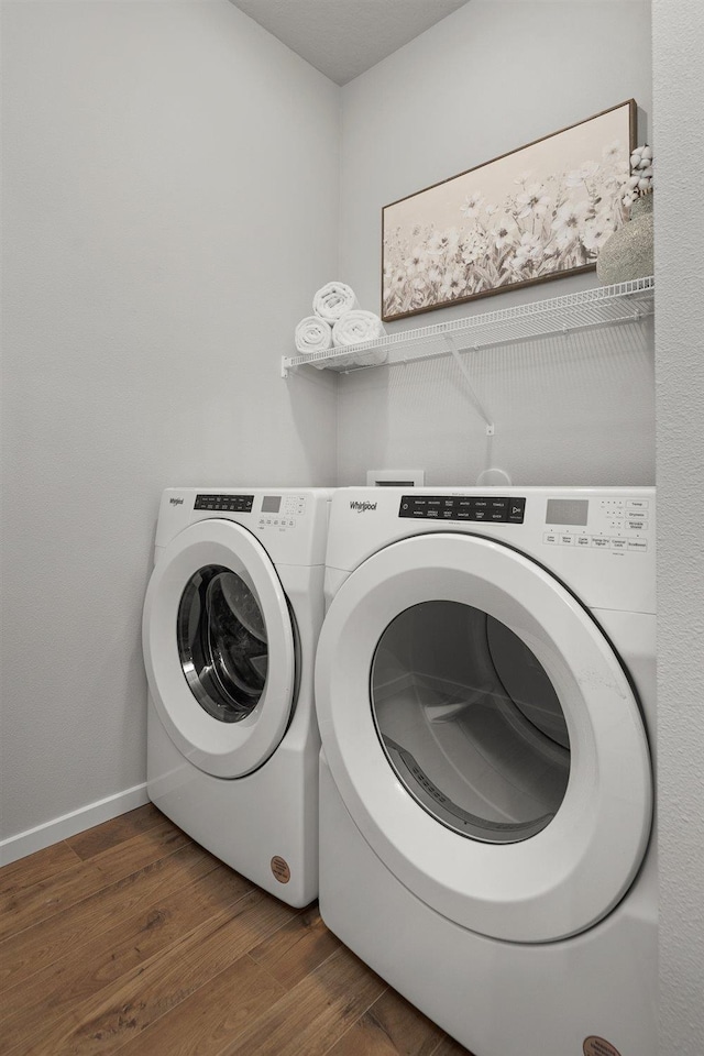 washroom with laundry area, dark wood finished floors, washer and clothes dryer, and baseboards