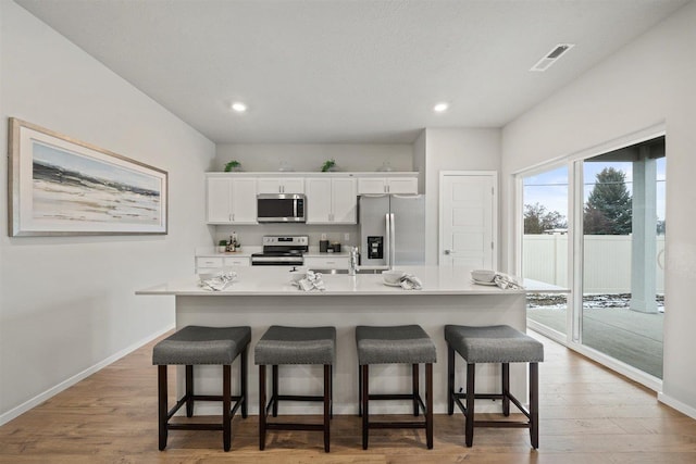 kitchen featuring a large island, white cabinetry, stainless steel appliances, and light countertops