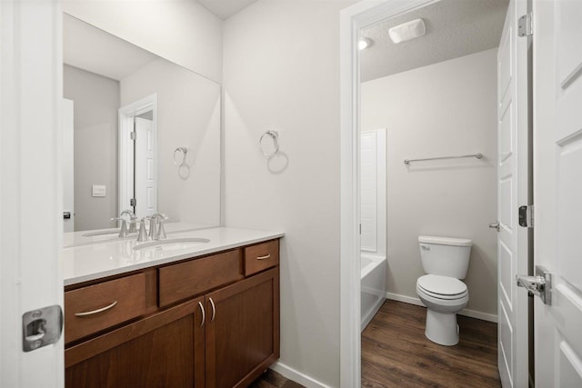 full bath featuring toilet, tub / shower combination, vanity, wood finished floors, and baseboards