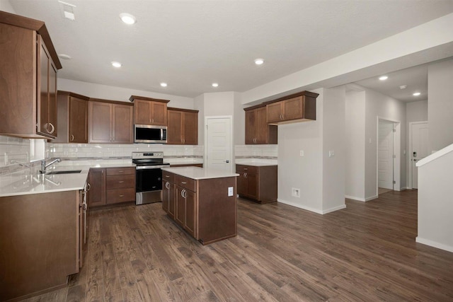 kitchen featuring stainless steel appliances, dark wood-type flooring, a kitchen island, light countertops, and decorative backsplash