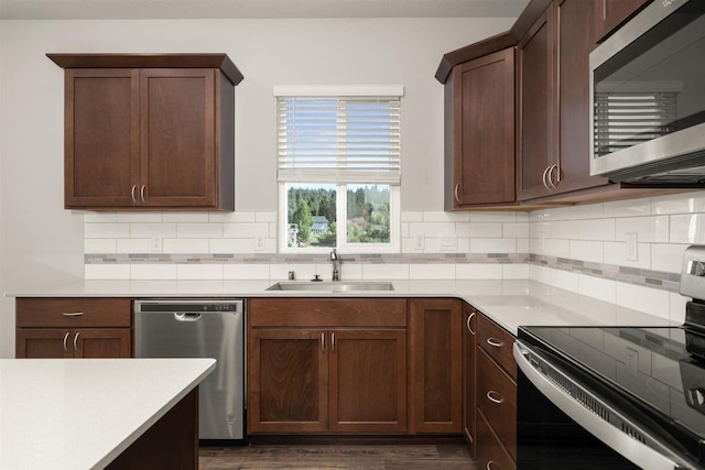 kitchen featuring a sink, light countertops, appliances with stainless steel finishes, dark brown cabinets, and decorative backsplash