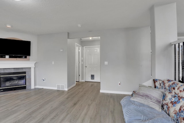 living area featuring light wood-style floors, baseboards, a fireplace, and visible vents