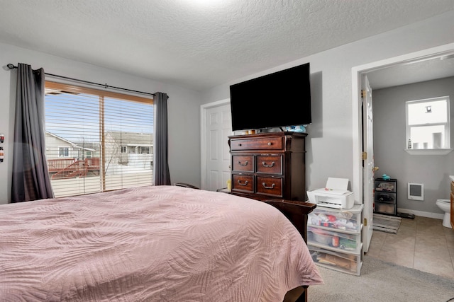 bedroom with carpet floors, visible vents, a textured ceiling, baseboards, and tile patterned floors